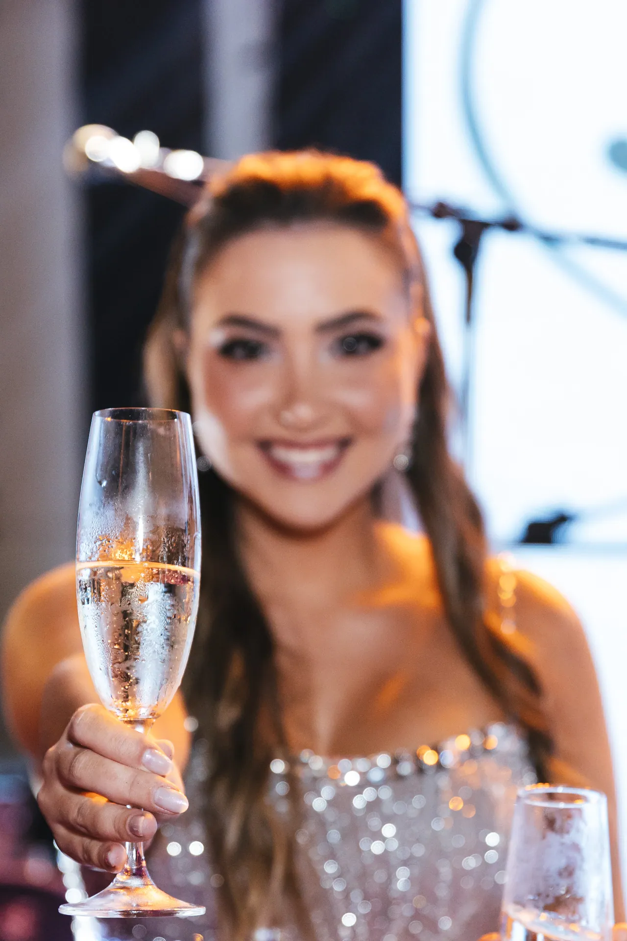 Formanda sorrindo ao erguer uma taça para brindar a conquista.