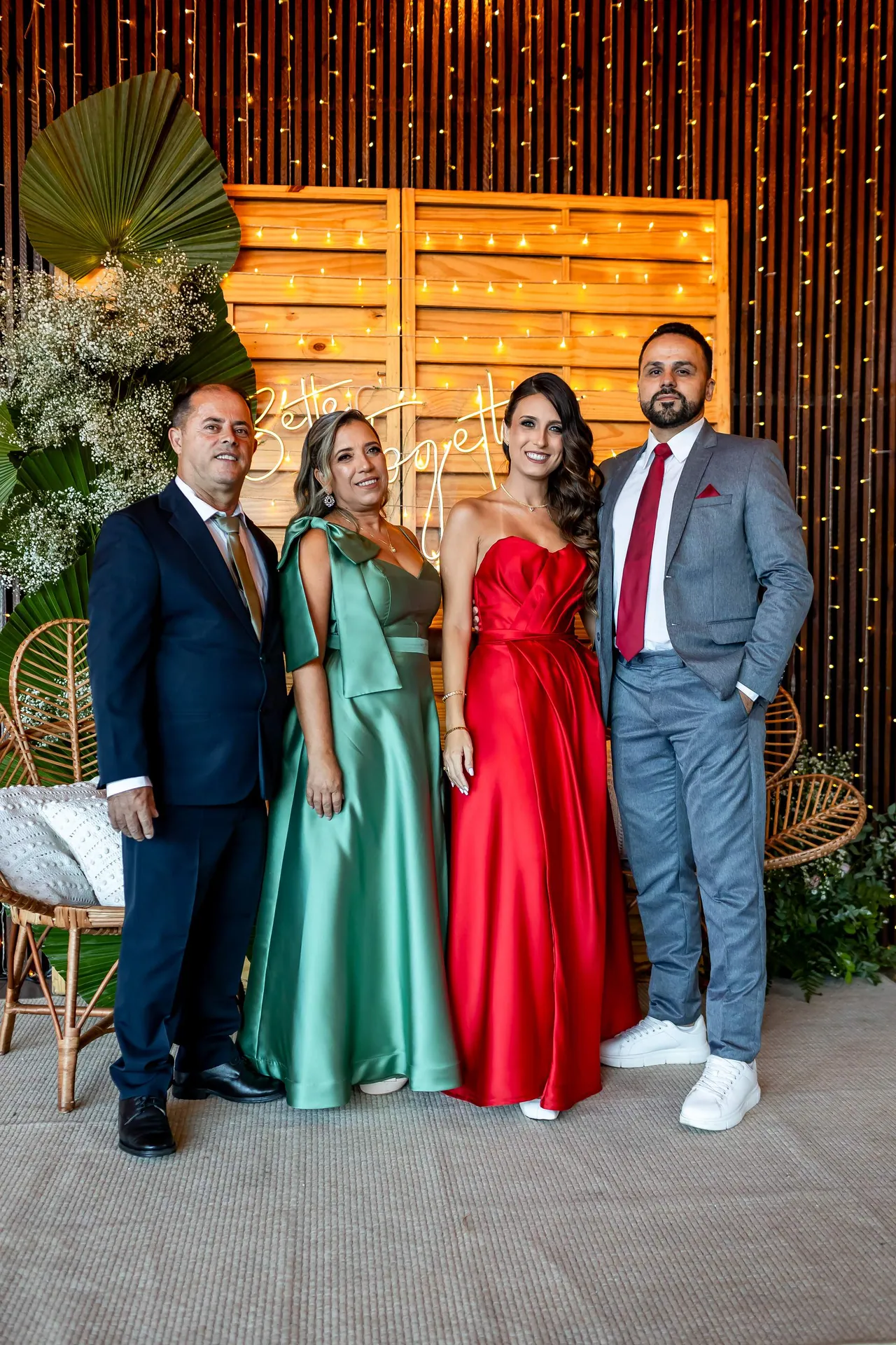 Formanda de vestido vermelho reunida com convidados em frente à decoração da festa.