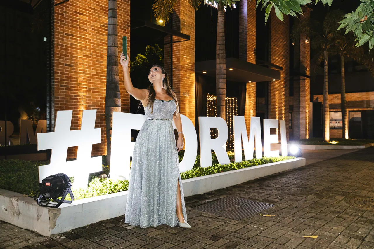 Formanda junto ao letreiro iluminado de formatura, diante do Indaiá em Joinville.