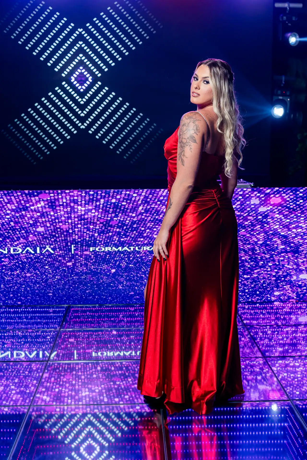 Formanda de vestido vermelho na pista iluminada em azul.