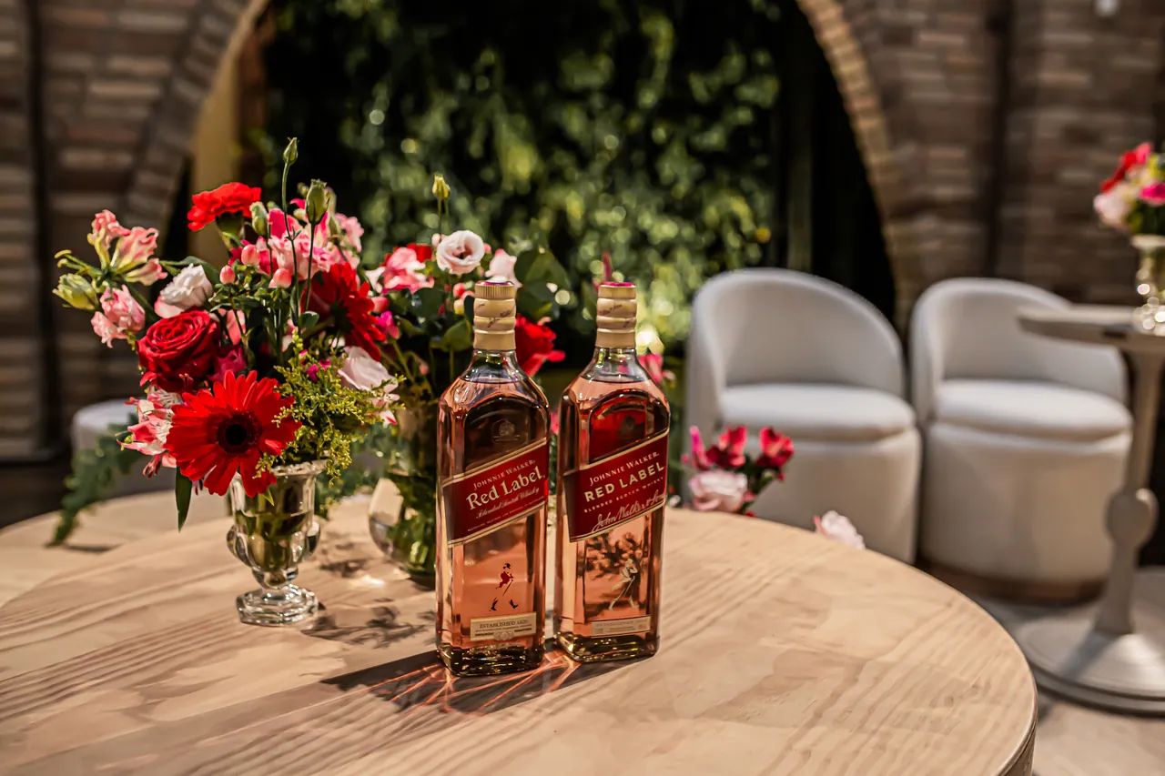 Mesa do lounge com flores vermelhas e bebidas para a celebração.